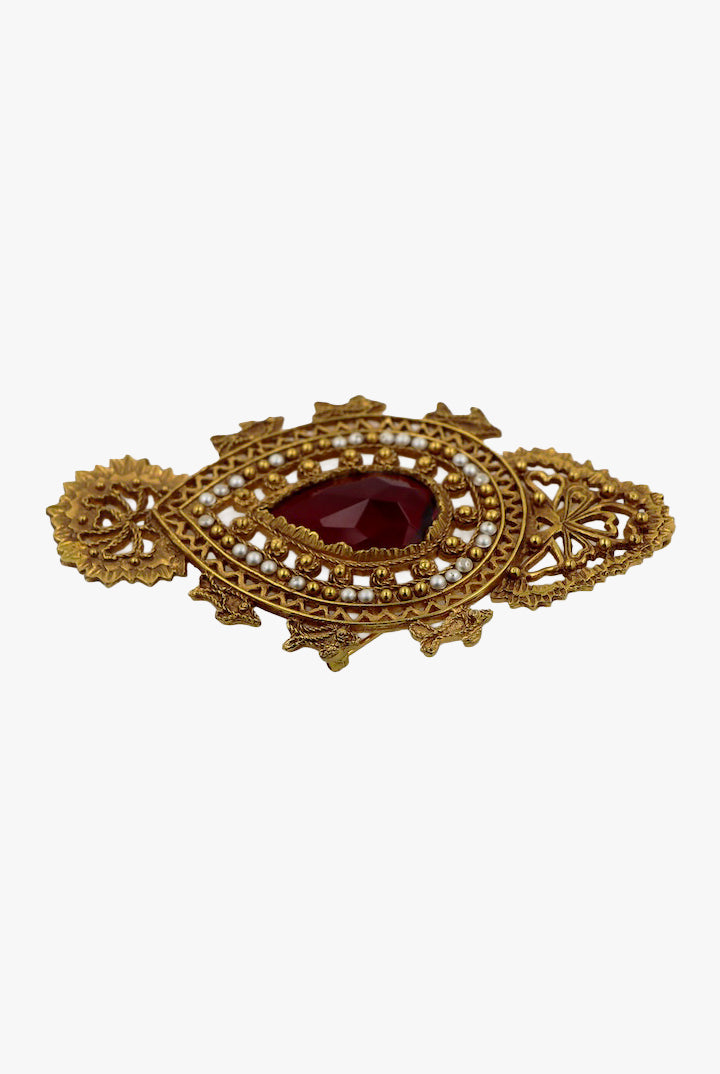 Broche vintage dorée avec détail centrale d'une pierre rouge et ornée de petites perles blanches