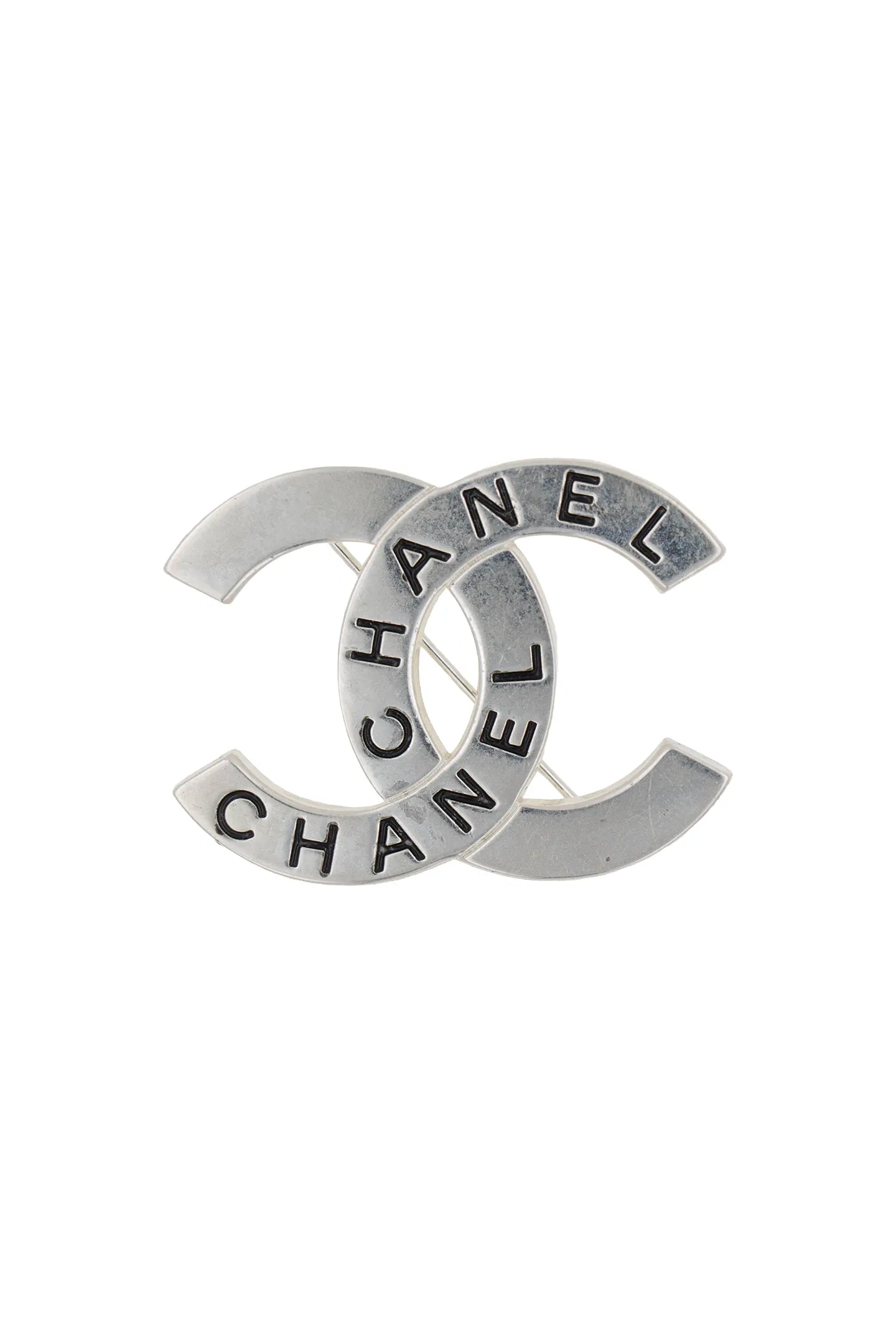 Broche Chanel vintage argentée, monogramme CC ajouré gravé du mot Chanel, éclat sophistiqué intemporel.