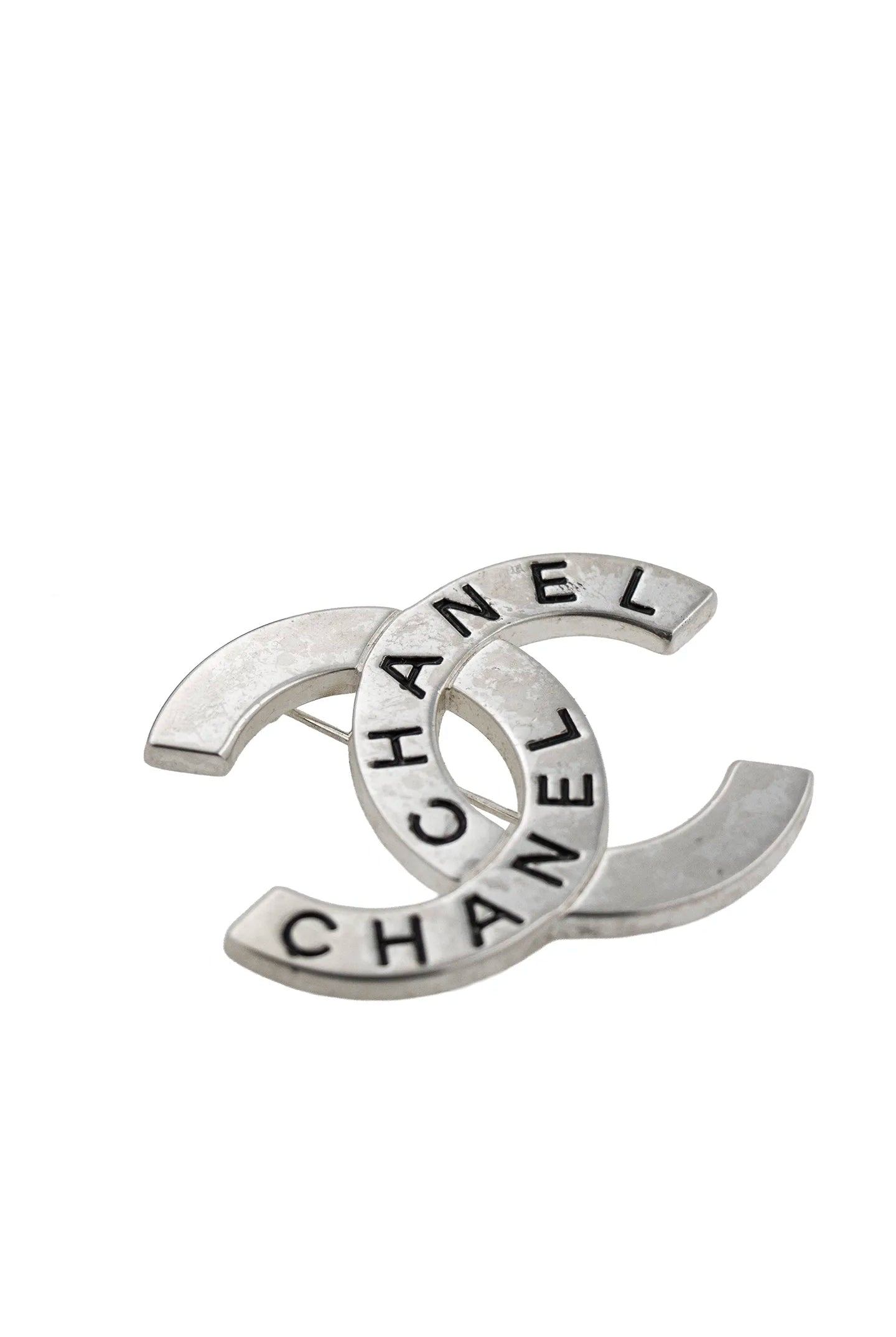 Broche double C Chanel vintage vue de profil, révélant le raffinement du travail du métal argenté.