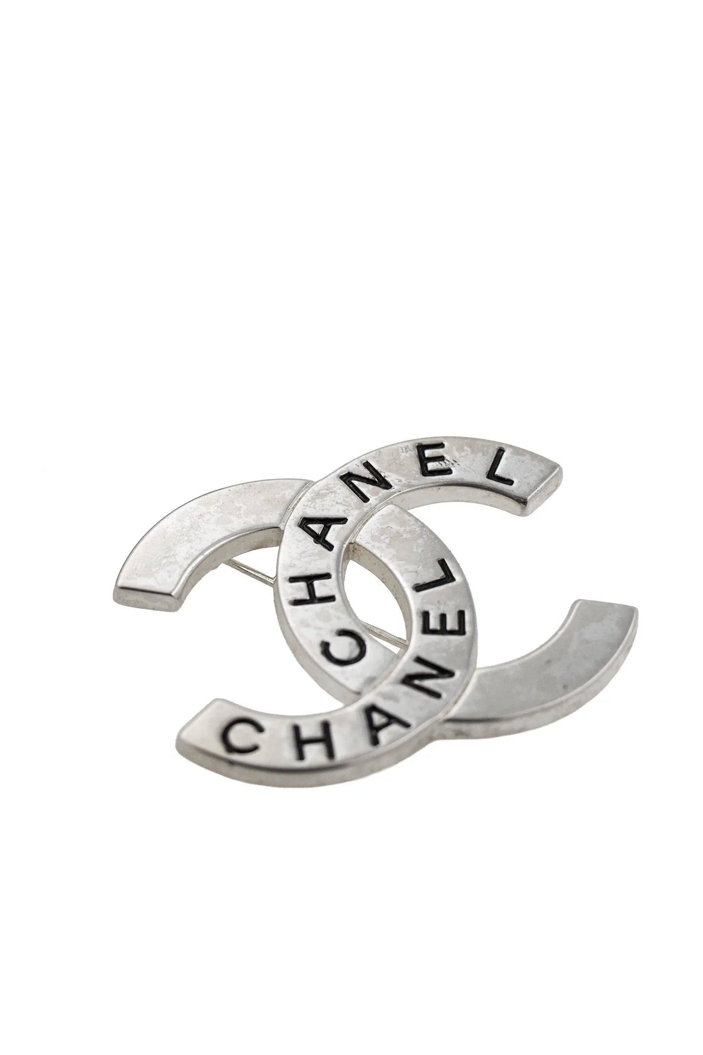 Broche double C Chanel vintage vue de profil, révélant le raffinement du travail du métal argenté.