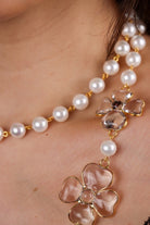 Détail collier long sautoir en perles blanches et motif de trèfle en pâte de verre transparent chaîne dorée