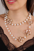 Long collier doré sautoir en perles blanches et motif trèfle à quatre feuille en pâte de verre transparent