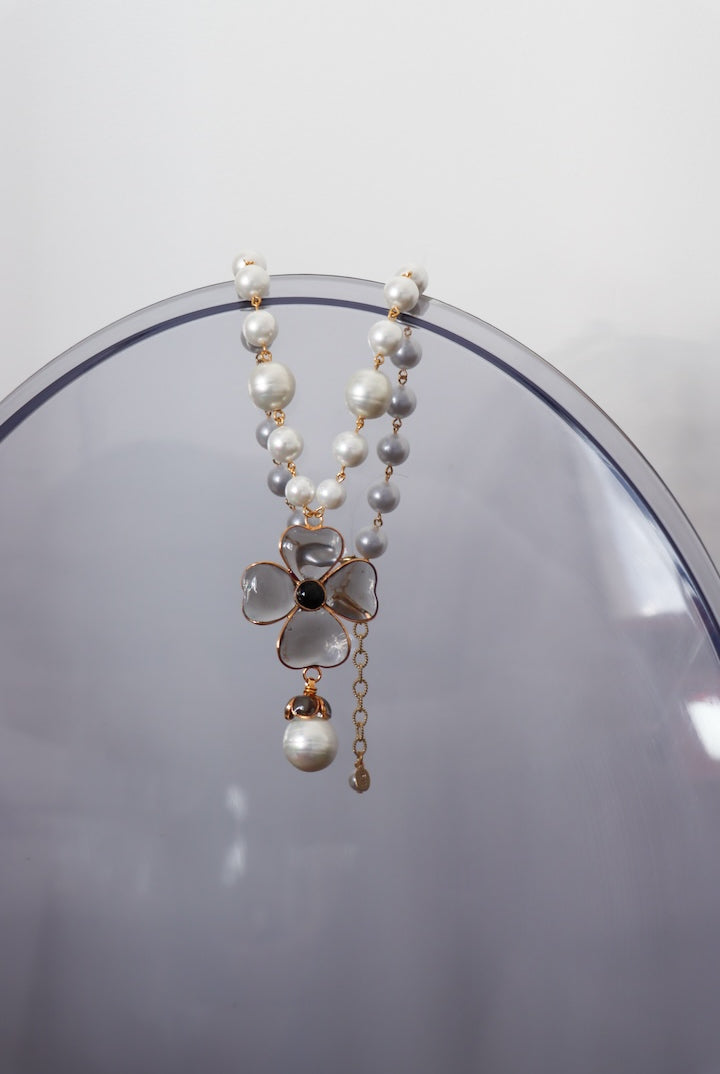 Collier en pâte de verre fumé gris et perles fantaisie pour femme sur un miroir
