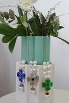 Trois Colliers fantaisie en perles blanches et motif trèfle à quatre feuille en pâte de vert bleu, vert et gris fumé