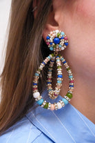 Boucles d'Oreilles en perles multicolore bleu, vert, rose et turquoise large et pendantes avec un fermoir clip portées à l'oreilles d'une femme