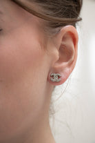 Petite Paire de boucles d'oreilles CC portée Chanel vintage, strass étincelants sur monture argentée texturée.