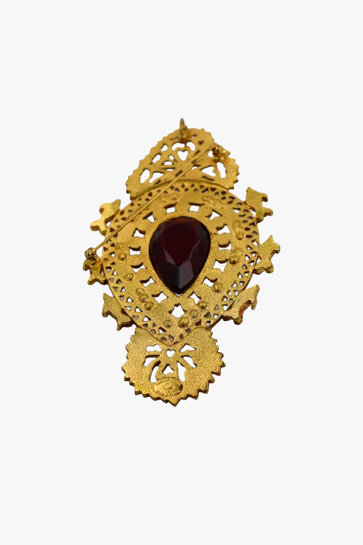 Grosse broche de créateur vintage dorée avec détail centrale  d'une pierre rouge et ornée de petites perles blanches 