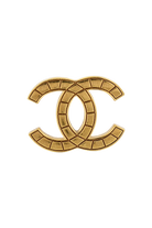 Broche CC vintage Chanel dorée, motif matelassé segmenté sur monture métal, pièce d'archive intemporelle.