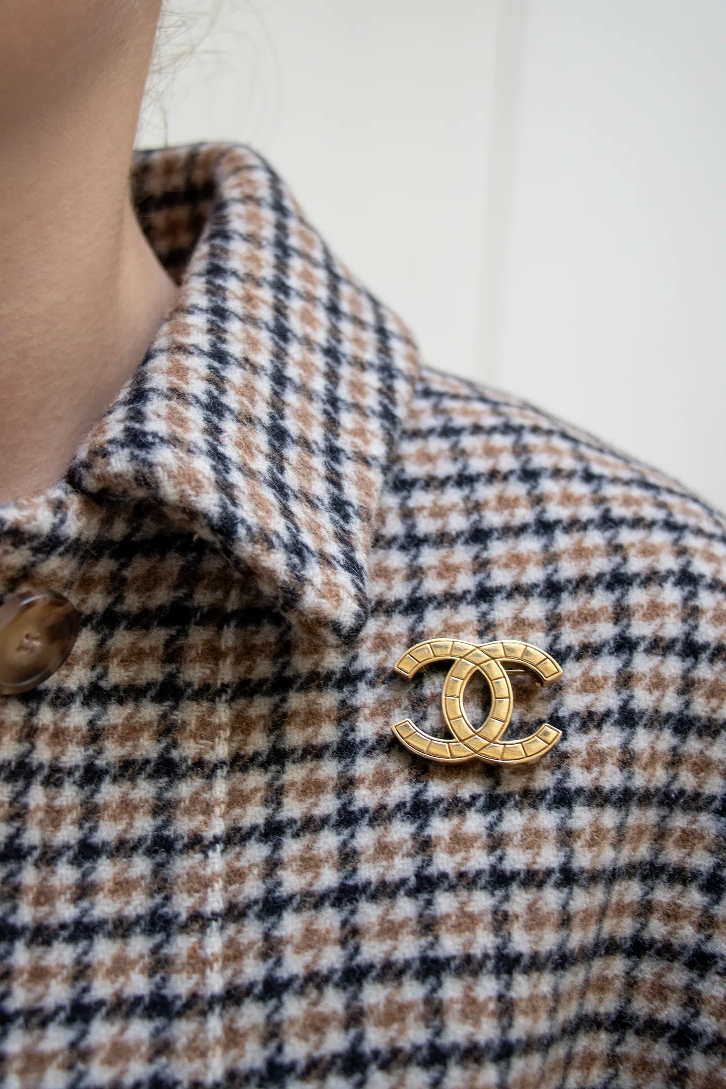 Broche CC vintage Chanel dorée portée col, motif matelassé segmenté sur monture métal, pièce d'archive intemporelle.