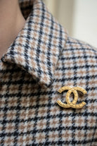 Détail portée zoom Broche CC vintage Chanel dorée, motif matelassé segmenté sur monture métal, pièce d'archive intemporelle.