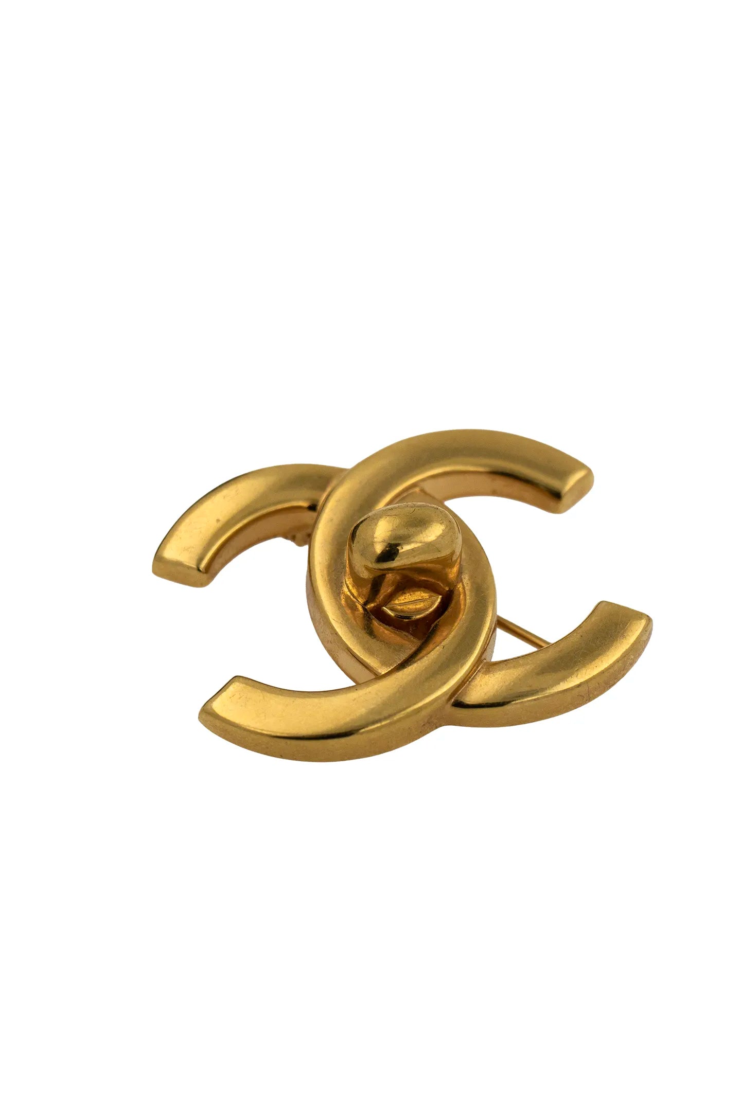 Éclat du métal doré poli sur le logo double C, lignes épurées et raffinement intemporel.