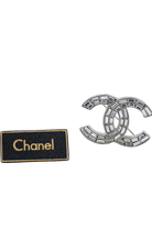 Broche Chanel vintage présentée avec son étiquette noire et dorée, gage d'authenticité et d'héritage.