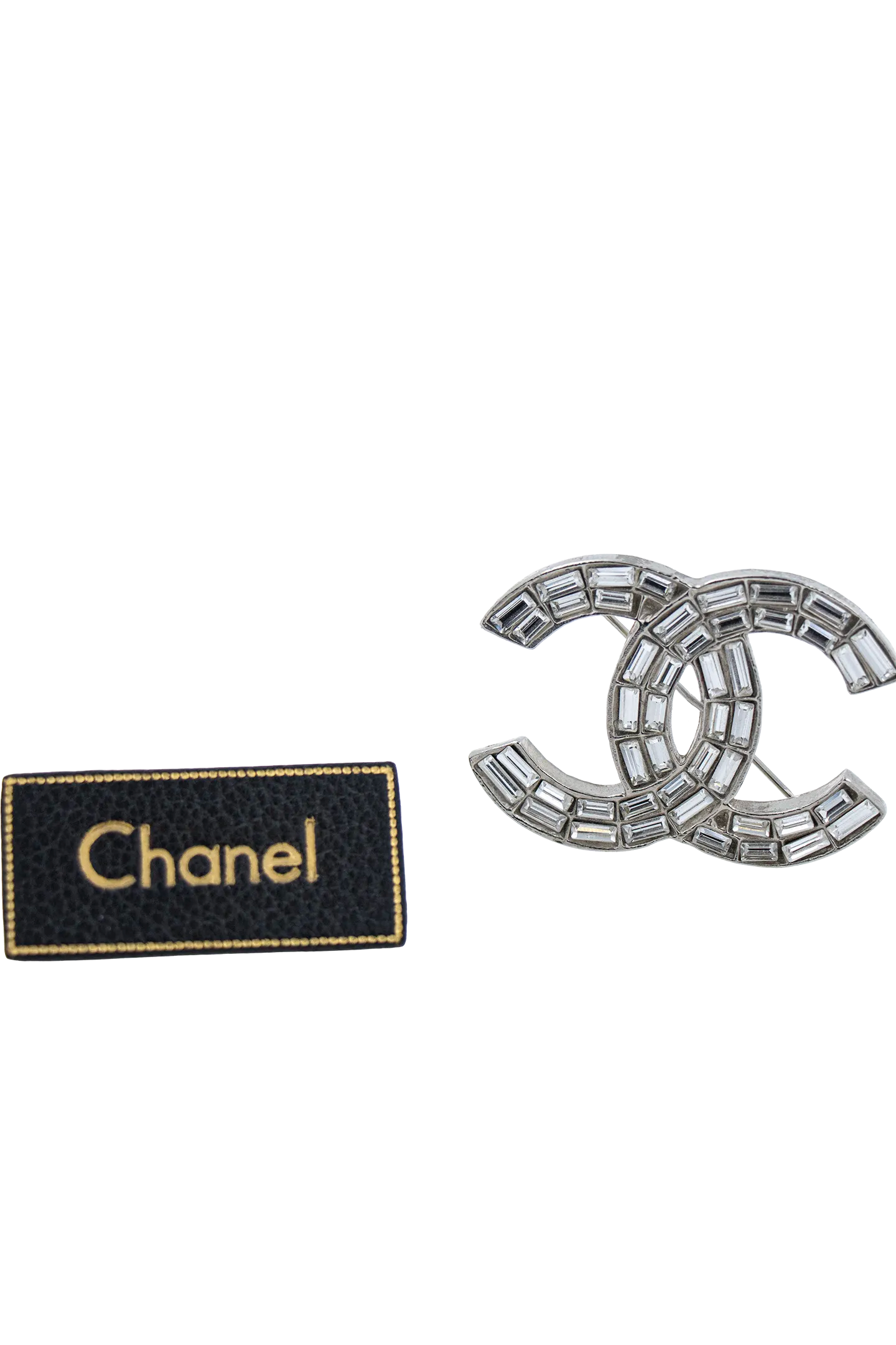 Broche Chanel vintage présentée avec son étiquette noire et dorée, gage d'authenticité et d'héritage.
