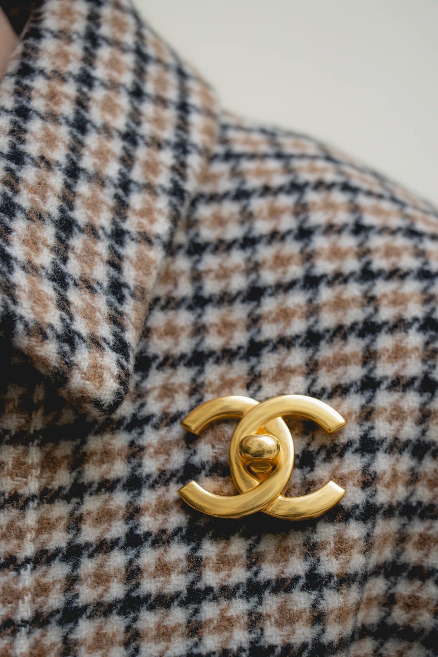 Éclat du métal doré poli sur le logo double C, lignes épurées et raffinement intemporel. Broche portée sur col 