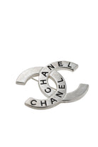 Broche double C Chanel vintage vue de profil, révélant le raffinement du travail du métal argenté.