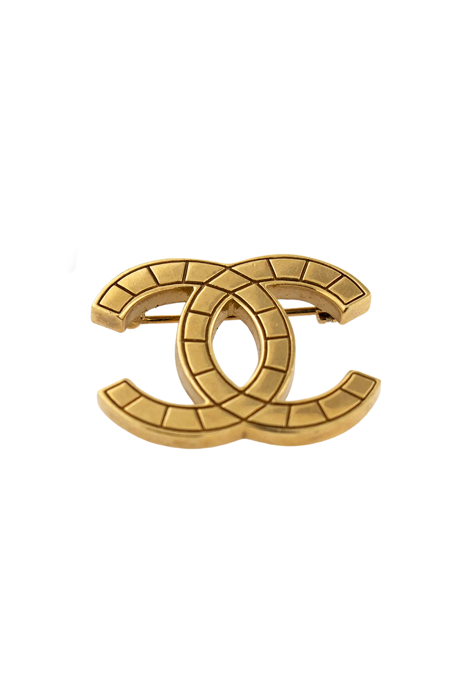 Broche Chanel vintage dorée présentée avec son étiquette noire et dorée, gage d'authenticité et d'héritage.