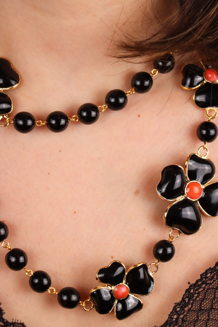 Collier long sautoir en perles noires et motif trèfles à quatre feuille noir centre rouge corail 